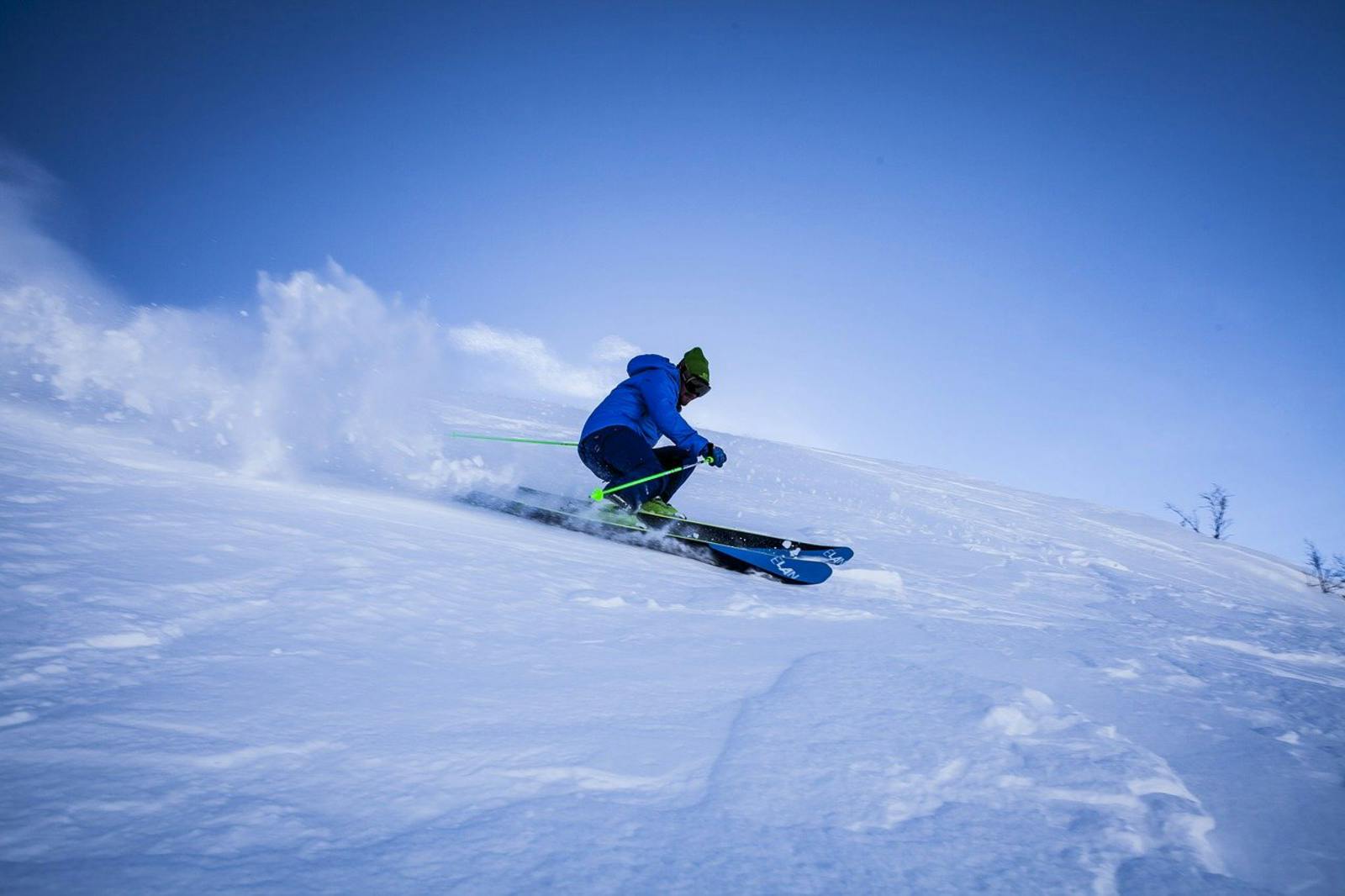 雪を巻き上げながら滑るスキーヤー