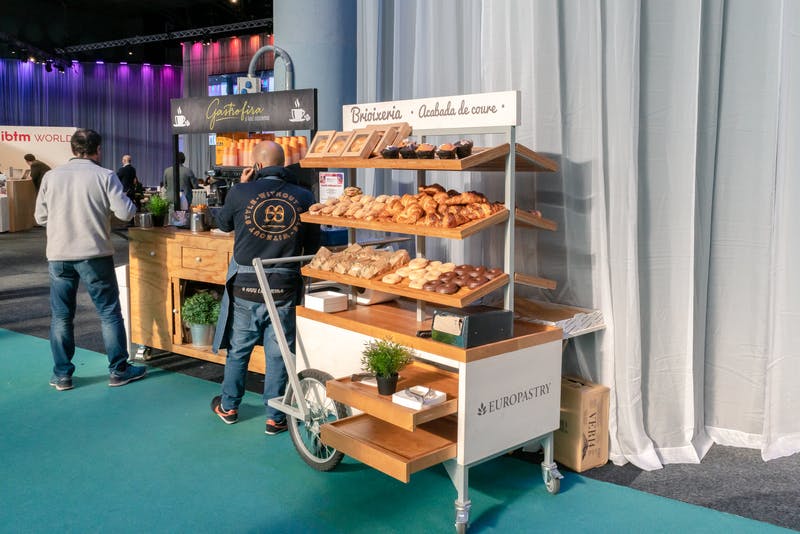 ▲IBTM World Barcelona：パンやコーヒーを片手に仕事をしている人