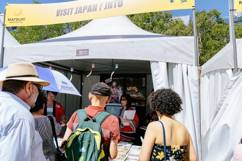 ▲Matsuri-Japan Festival：パンフレット説明をするスタッフと持っていくものを吟味する来場者