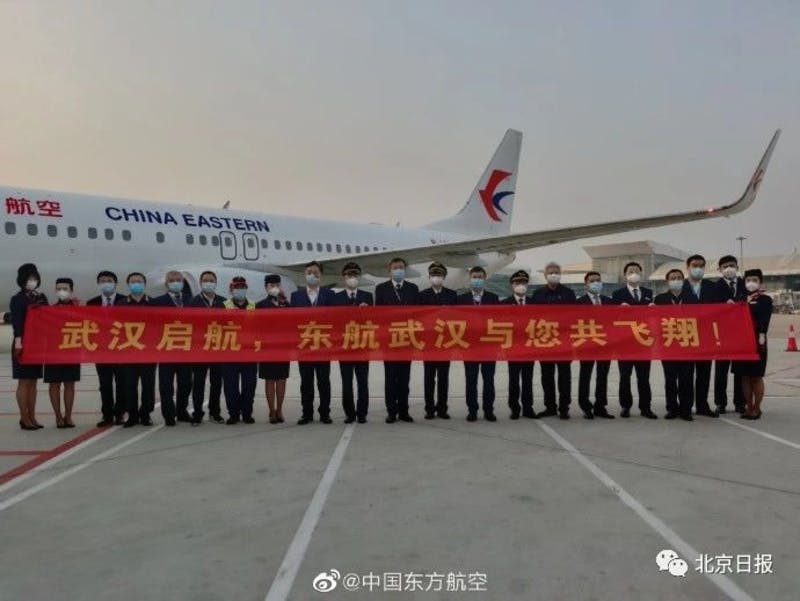 飛行機の前に、横断幕を持った航空会社の中国人社員が横一列に並ぶ